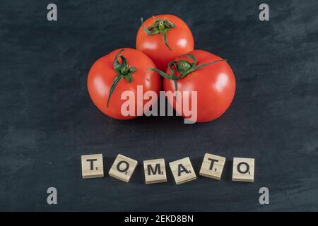 Trois tomates entières fraîches sur fond sombre Banque D'Images