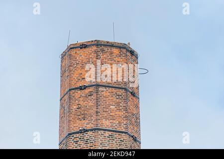 Cheminée en briques rouges et un kestrel assis sur le dessus. Jour d'hiver ensoleillé avec ciel bleu clair en arrière-plan. Banque D'Images