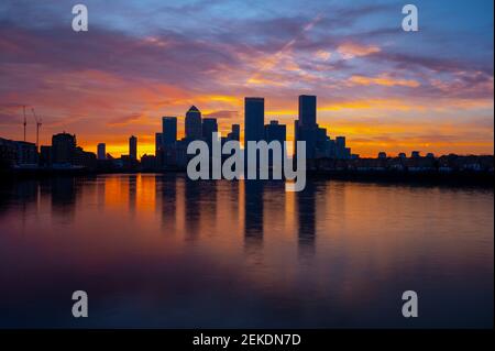 Un lever de soleil spectaculaire au-dessus de Canary Wharf, capitale financière du Royaume-Uni, Londres, avec la Tamise en premier plan reflétant le ciel violet et jaune Banque D'Images