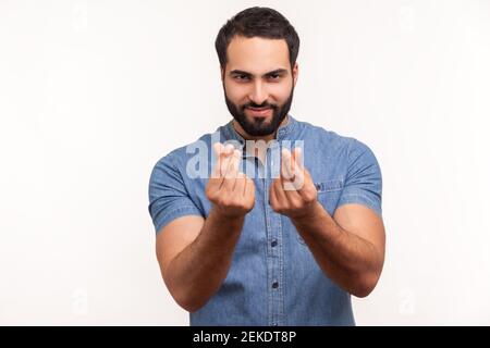 Homme mercantile rusé avec la barbe, se frottant les doigts montrant le geste d'argent, demandant le salaire, exigeant des pots-de-vin, regardant la caméra avec le sourire. Salle de studi Banque D'Images