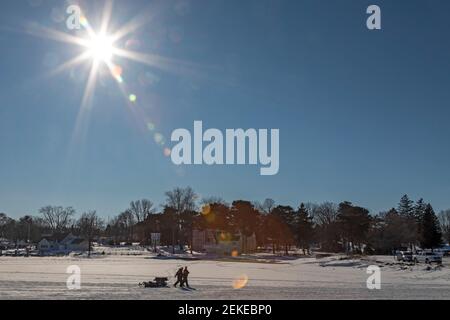 Port Sanilac, Michigan - les pêcheurs de glace traînent leur équipement jusqu'au rivage après avoir pêché sur la glace du port de Port Sanilac, sur le lac Huron. Banque D'Images
