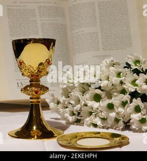 Un calice doré aux fleurs blanches et à la bible. Religion. Christianisme. Sainte communion. Thème catholique. Banque D'Images