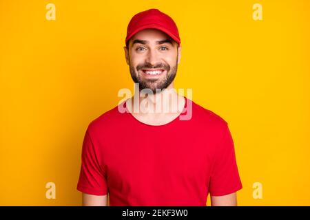 Photo portrait du liveur portant une casquette rouge uniforme souriant isolé sur fond jaune vif Banque D'Images