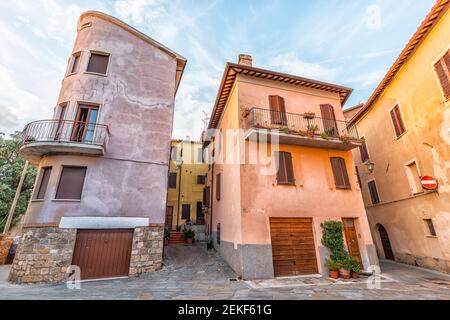 Chiusi, Italie orange rose violet jaune vif coloré multicolore mur au coucher du soleil rue dans petit village en Toscane avec garage Banque D'Images