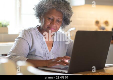 Femme afro-américaine réfléchie utilisant un ordinateur portable à la maison Banque D'Images