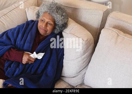 Femme sénior afro-américaine malade assise sur le canapé Banque D'Images