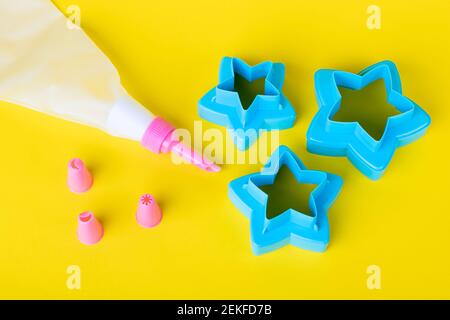 Emporte-pièces en forme d'étoile. Outils de décoration de gâteau, sac de pâtisserie avec des buses sur un fond jaune pour la décoration de gâteau. Concept de cuisine de confiserie W Banque D'Images