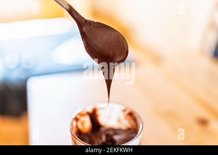 Gros plan sur une cuillère de sauce crémeuse au chocolat et aux noisettes mousser le glaçage à la crème sur fond flou bokeh Banque D'Images