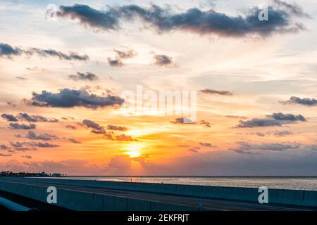 Lever du soleil à Islamorada, la Floride touche avec un ciel orange coloré par pont routier d'outre-mer au golfe du Mexique avec des nuages dans le ciel nuageux Banque D'Images