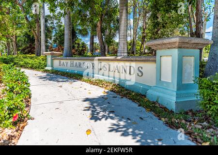 Bay Harbour Islands signe pour Miami Dade County, Floride par Biscayne Bay dans le parc public avec chemin pavé et personne par les palmiers Banque D'Images