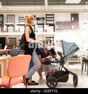 Jeune couple avec nouveau-né dans le magasin de poussettes au détail de meubles et maison accessoires magasin portant un masque médical de protection pour le visage à prévenir Banque D'Images