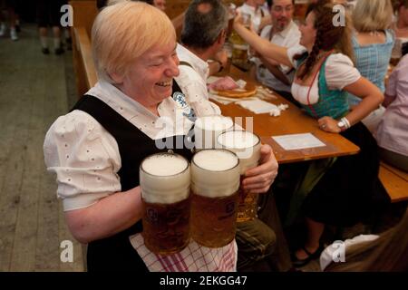 Allemagne serveuse Munch transportant de grandes tasses de bière de taille litre à L'Octoberfest sur la Theresienwiese à Munich Banque D'Images