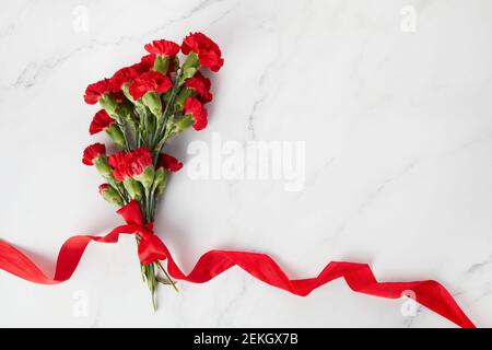 Fleurs de la carnation béaytiful avec ruban rouge sur fond de marbre. Vue de dessus Banque D'Images