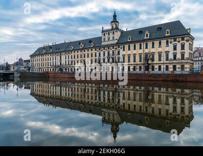 Wroclaw, Pologne - Mars 19 2020 façade de l'Université de Wroclaw au matin nuageux reflété dans la rivière silencieuse Odra Banque D'Images