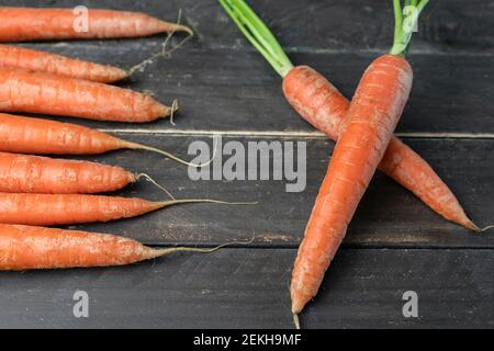 Bouquet de carottes avec deux carottes fraîches croisées sur bois Background.Creative saine alimentation mode de vie, légumes crus modèle concept Banque D'Images