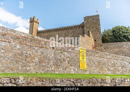 Montalcino, Italie - 26 août 2018 : petit village médiéval historique en Toscane. Journée ensoleillée d'été avec murs de pierre, forteresse, tour de fort et bannière Banque D'Images