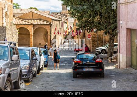 Montalcino, Italie - 26 août 2018 : petit village médiéval historique en Toscane, jour d'été avec drapeaux rouges, personnes dans la rue et en voiture Banque D'Images