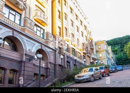 Kiev, Ukraine - 10 août 2018: Andriyivskyy Uzviz Podil zone à l'architecture traditionnelle, route de rue abrupte de colline et coucher de soleil sur la construction avec des voitures Banque D'Images