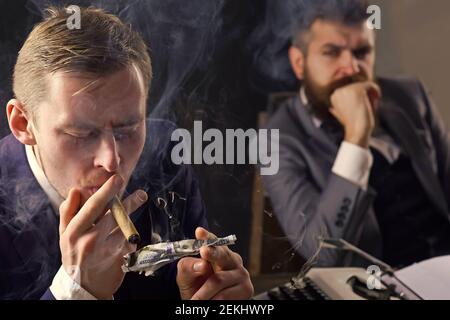 Homme éclairant le cigare d'un billet de banque en feu de dollar. Réunion d'affaires. Gangster et argent. Concept de crime. Fond fumé. Style rétro et vintage. Banque D'Images