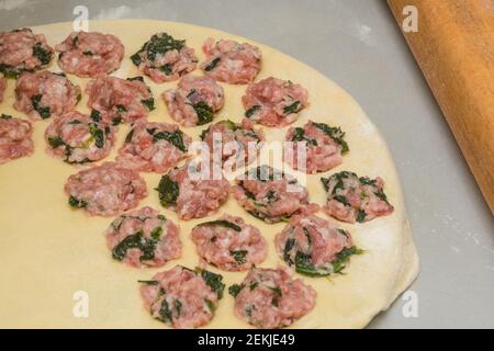 Processus de cuisson des boulettes maison. Viande hachée aux épinards sur une croûte mince. Gros plan, mise au point sélective. Banque D'Images