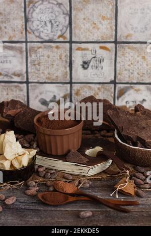 Chocolat à pâte non sucré, poudre de cacao, beurre de cacao et fèves de cacao sur fond de bois ancien Banque D'Images