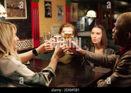 Les jeunes assis à la table buvant de la bière pendant leur réunion au pub Banque D'Images
