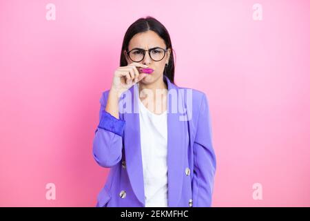 Jeune femme d'affaires portant une veste violette sur fond rose bouche et lèvres fermées comme zip avec les doigts. Secret et silencieux, tabou parlant Banque D'Images