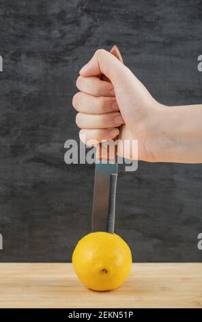 Femme coupant à la main un citron frais juteux sur un sombre arrière-plan Banque D'Images