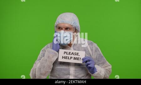 Médecin travailleur médecin médecin en costume PPE avec texte inscription slogan sur papier - s'il vous plaît, aide Me. isolé sur chroma fond clé en attente de vaccination injection contre le coronavirus covid-19 pandémie Banque D'Images