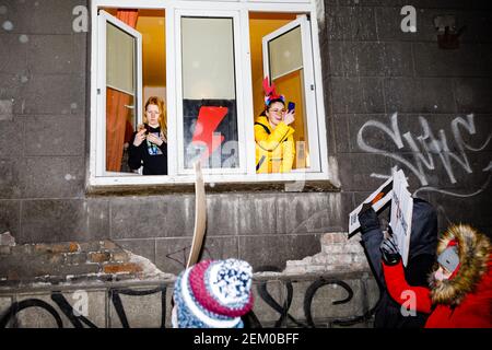 Deux jeunes femmes sont vues avec des smartphones prenant des photos des manifestants par les fenêtres ouvertes de leur appartement. Un éclairage rouge, le symbole des femmes Banque D'Images
