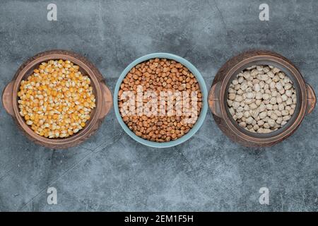 Différents types de haricots et de cornes non cuits dans divers pots Banque D'Images