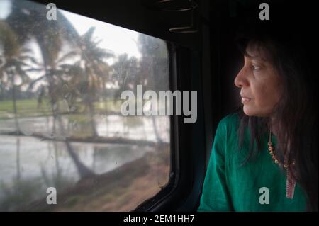 Une femme indienne regarde par la fenêtre du train pendant qu'elle passe Par les zones rurales de l'Andhra Pradesh Banque D'Images