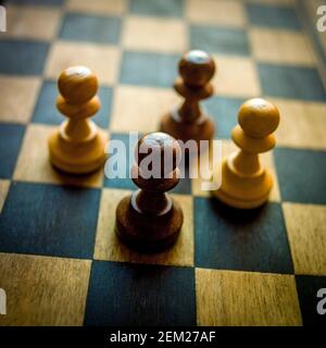 Pions d'échecs dans une position stratégique sur une planche de bois lors d'une partie intense Banque D'Images