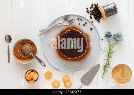 Tiramisu maison ronde, sans cuisson dessert sucré traditionnel italien. Tableau bleu avec du gâteau, bol avec la poudre de cacao, biscuits éponge ronde, les grains de café Banque D'Images