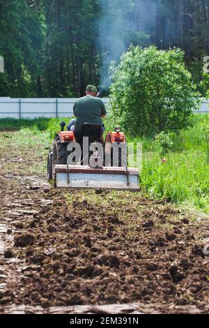 Défrichement et nivellement d'un terrain privé. Un cultivateur sur piste creuse un terrain privé Banque D'Images
