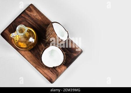 Half cut coconut and bottle of oil on the wooden board Banque D'Images