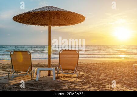 Deux chaises sous un parasol sur la plage tropicale au coucher du soleil. Concept de vacances d'été. Banque D'Images