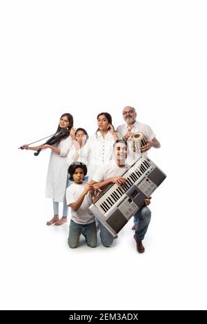 Concert d'une famille indienne de six personnes jouant des instruments de musique dans un groupe et une femme âgée chantant, debout sur fond blanc Banque D'Images