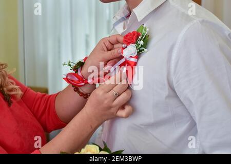 la mariée ajuste la boutonnière du marié. Sans visage. Banque D'Images