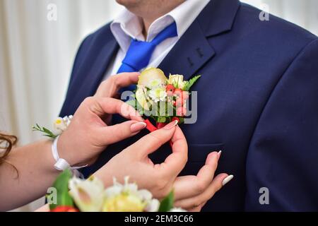 la mariée ajuste la boutonnière du marié. gros plan. Banque D'Images