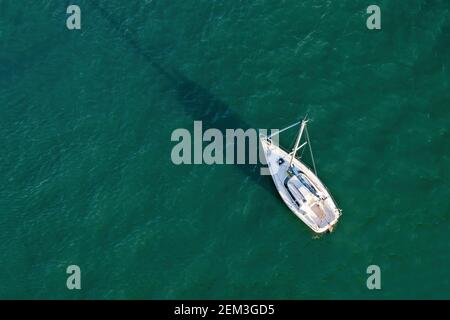 Vue aérienne par drone d'un bateau à voile sur l'eau émeraude Banque D'Images