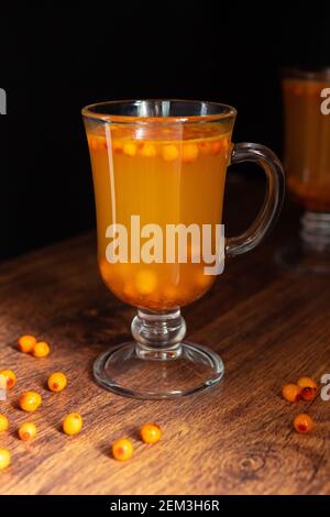 Boissons chaudes de l'argousier dans deux verres sur fond noir. Le concept des boissons chaudes de saison. Baies d'argousier à proximité. Boissons saines. Banque D'Images