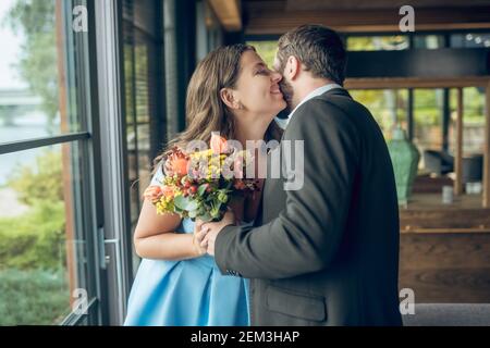 Homme avec des fleurs et une femme heureuse debout embrassant Banque D'Images