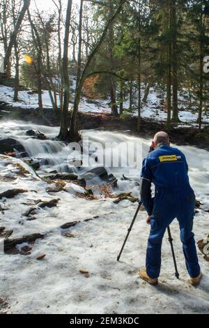 Alexisbad, Allemagne. 24 février 2021. Un travailleur passe sa pause déjeuner aux chutes Selke et prend des photos avec son trépied des masses d'eau qui se précipitent sur les cascades de la vallée. Le dégel s'est également installé dans les montagnes Harz. Ce n'est que dans les forêts que les champs de neige ont survécu aux températures printanières. Il est censé rester ensoleillé toute la semaine, mais il va de nouveau se refroidir à la fin de la semaine. Credit: Klaus-Dietmar Gabbert/dpa-Zentralbild/dpa/Alay Live News Banque D'Images