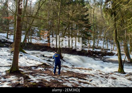 Alexisbad, Allemagne. 24 février 2021. Un travailleur passe sa pause déjeuner aux chutes Selke et prend des photos avec son trépied des masses d'eau qui se précipitent sur les cascades de la vallée. Le dégel s'est également installé dans les montagnes Harz. Ce n'est que dans les forêts que les champs de neige ont survécu aux températures printanières. Il est censé rester ensoleillé toute la semaine, mais il va de nouveau se refroidir à la fin de la semaine. Credit: Klaus-Dietmar Gabbert/dpa-Zentralbild/dpa/Alay Live News Banque D'Images