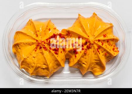Garniture à la crème d'antipasti orange avec morceaux de poivre sur le dessus dans un emballage en plastique transparent vue de haut en bas. Banque D'Images