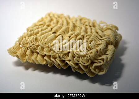 Vermicelles instantanées, briquette de vermicelles minces et longues sur fond blanc. Banque D'Images