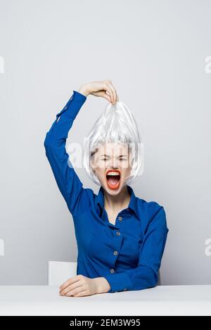 la femme prend la perruque blanche de la tête des émotions assis à boisson de table Banque D'Images