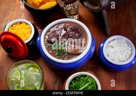 Feijoada brésilienne, cuisine traditionnelle avec diverses viandes de porc accompagnées de chou, riz, caipirinha, farofa Banque D'Images