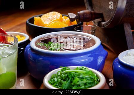 Feijoada brésilienne, cuisine traditionnelle avec diverses viandes de porc accompagnées de chou, riz, caipirinha, farofa Banque D'Images